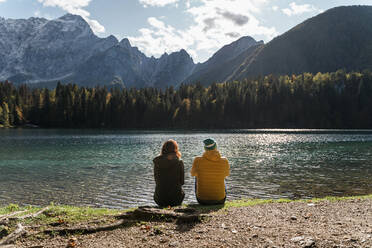 Rückansicht eines Paares am Seeufer von Laghi di Fusine, Friaul-Julisch-Venetien, Italien - MAUF03225