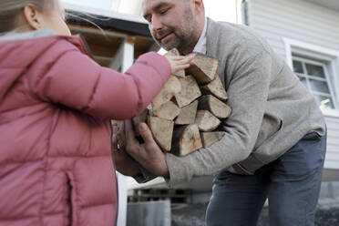 Mann trägt Brennholz, Tochter gibt ihm Holz - KMKF01198