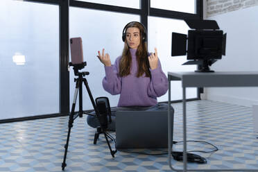 Porträt einer jungen Frau, die mit Laptop und Smartphone in einem Studio Aufnahmen macht - ERRF02592