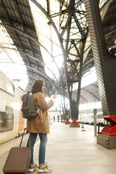Junge Frau benutzt ein Handy am Bahnhof - VABF02492