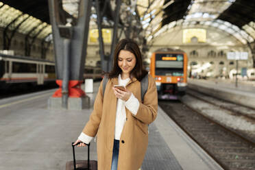 Junge Frau benutzt ein Handy am Bahnhof - VABF02499