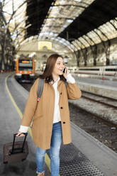 Young woman talking on the phone at the train station - VABF02500