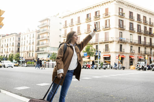 Junge Frau in der Stadt, die ein Taxi ruft, Barcelona, Spanien - VABF02517