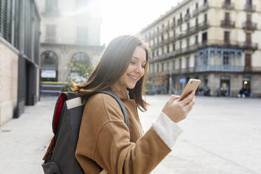 Happy young woman using cell phone in the city, Barcelona, Spain - VABF02526