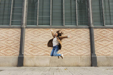 Aufgeregte junge Frau beim Springen in der Stadt - VABF02527