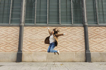 Excited young woman jumping in the city - VABF02527