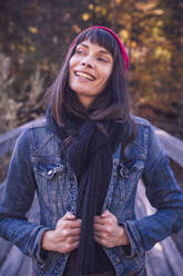 Portrait of smiling woman wearing red woolly hat and denim jacket - DHEF00030