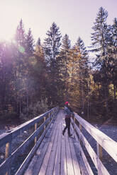 Woman wearing red woolly hat and denim jacket on a bridge in autumn - DHEF00037