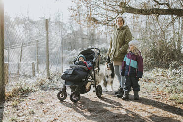 Mother with children and border collie during forest walk in autumn - DWF00531