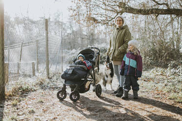 Mutter mit Kindern und Border Collie bei einem Waldspaziergang im Herbst - DWF00531