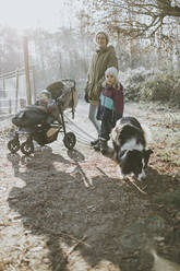 Mother with daughters and border collie during forest walk in autumn - DWF00533