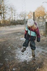 Girl kicking on frozen puddle - DWF00534