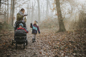 Mutter mit Töchtern bei einem Waldspaziergang im Herbst - DWF00545