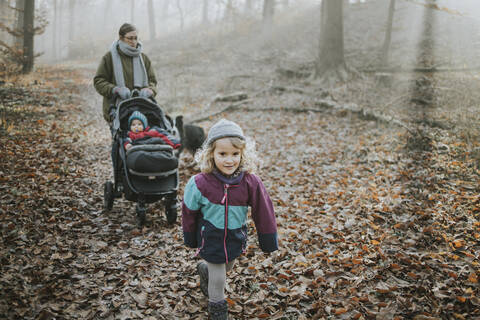 Mutter mit Töchtern und Border Collie bei einem Waldspaziergang im Herbst, lizenzfreies Stockfoto