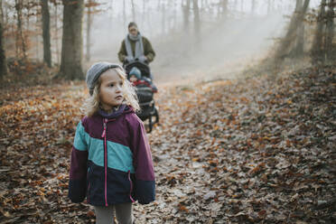 Mutter mit Töchtern bei einem Waldspaziergang im Herbst - DWF00549