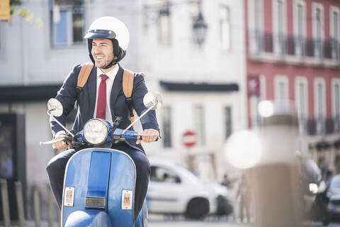 Young businessman riding motor scooter in the city, Lisbon, Portugal stock photo