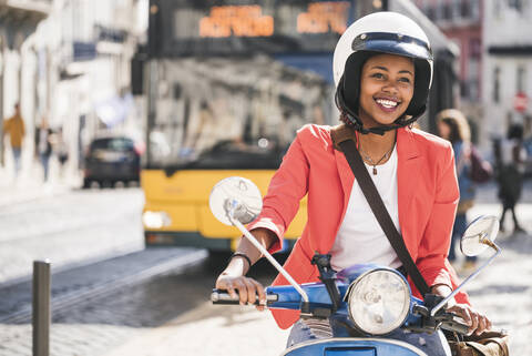 Glückliche junge Frau auf einem Motorroller in der Stadt, Lissabon, Portugal, lizenzfreies Stockfoto