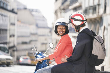 Happy young business couple on motor scooter in the city, Lisbon, Portugal - UUF20116