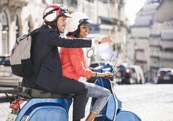 Glückliches junges Geschäftspaar fährt Motorroller in der Stadt, Lissabon, Portugal - UUF20118