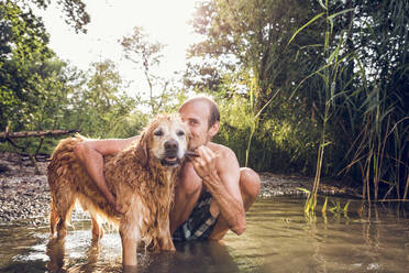 Mann mit seinem Golden Retriever am Seeufer - MAMF01040