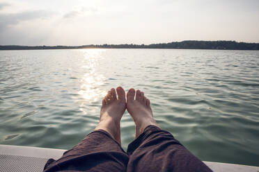 Man barefoot on sailing boat at sunset - MAMF01042