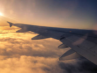 Flugzeugflügel im Flug über den Wolken bei Sonnenuntergang - TEBF00020