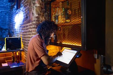Junger Mann, der in einer Bar arbeitet und eine Computerkasse benutzt - CJMF00236