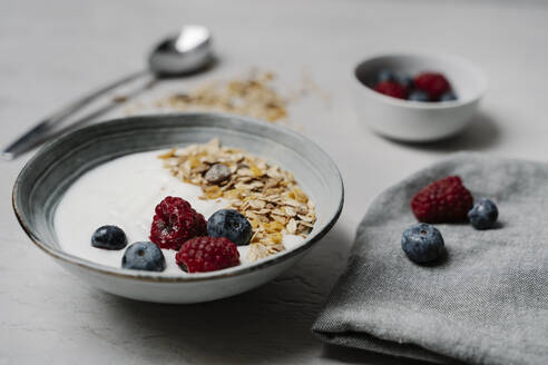 Bowl of granola with yogurt, blueberries and raspberries - JMHMF00039