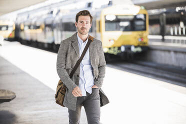 Selbstbewusster junger Geschäftsmann beim Spaziergang am Bahnhof - UUF20144