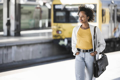 Lächelnde junge Frau auf dem Bahnhof, lizenzfreies Stockfoto