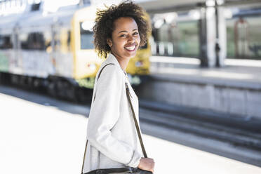 Porträt einer glücklichen jungen Frau auf dem Bahnhof - UUF20159