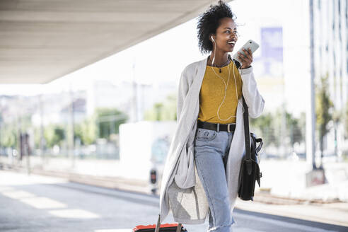 Smiling young woman on the go using smartphone at the train station - UUF20166