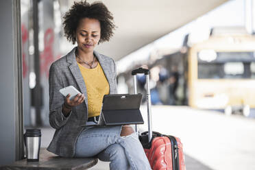 Junge Geschäftsfrau mit Tablet und Smartphone am Bahnhof - UUF20177