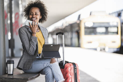 Young businesswoman using tablet and smartphone at the train station - UUF20179