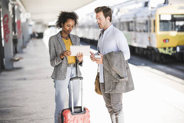 Young businessman and businesswoman using tablet together at the train station - UUF20183