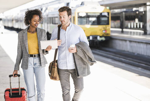 Young businessman and businesswoman using tablet together at the train station - UUF20185