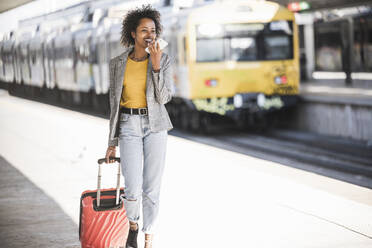 Lächelnde junge Frau beim Telefonieren am Bahnhof - UUF20191