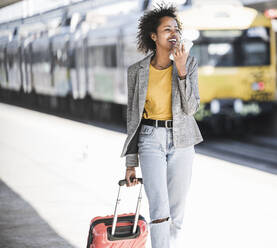 Happy young woman using cell phone at the train station - UUF20192