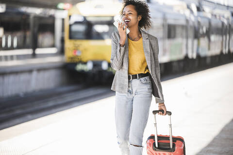 Glückliche junge Frau mit Handy am Bahnhof, lizenzfreies Stockfoto
