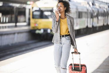 Happy young woman using cell phone at the train station - UUF20193