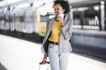 Lächelnde junge Frau beim Telefonieren am Bahnhof - UUF20194