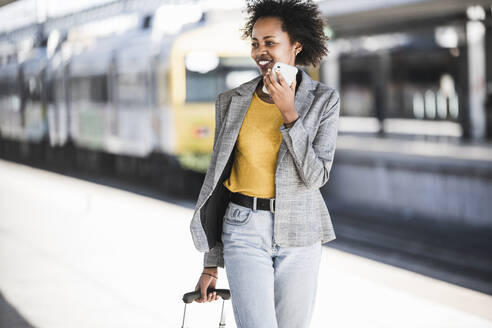 Smiling young woman using cell phone at the train station - UUF20194