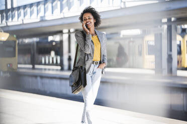 Happy young woman on the phone at the train station - UUF20195