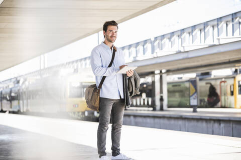 Lässiger junger Geschäftsmann mit Tablet am Bahnhof, lizenzfreies Stockfoto