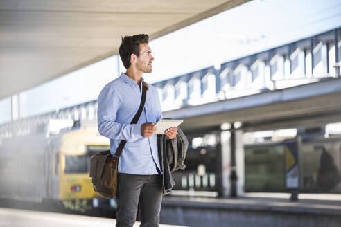 Casual young businessman using tablet at the train station - UUF20198