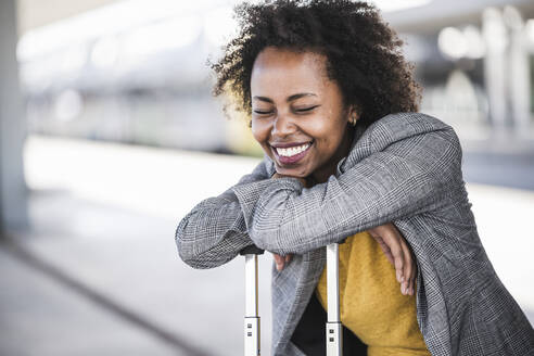 Happy young businesswoman with suitcase at the train station - UUF20203