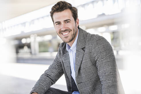 Portrait of smiling young businessman at the train station - UUF20209