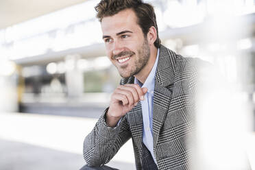 Portrait of smiling young businessman at the train station - UUF20210