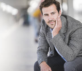 Portrait of young businessman sitting at the train station - UUF20213