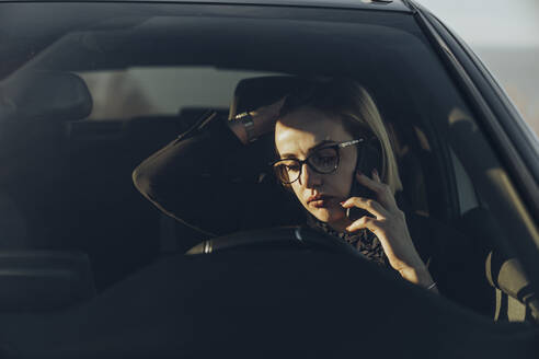Junge blonde Geschäftsfrau benutzt Smartphone im Auto - MTBF00312